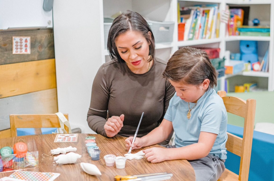 A student working on a craft project with an adult